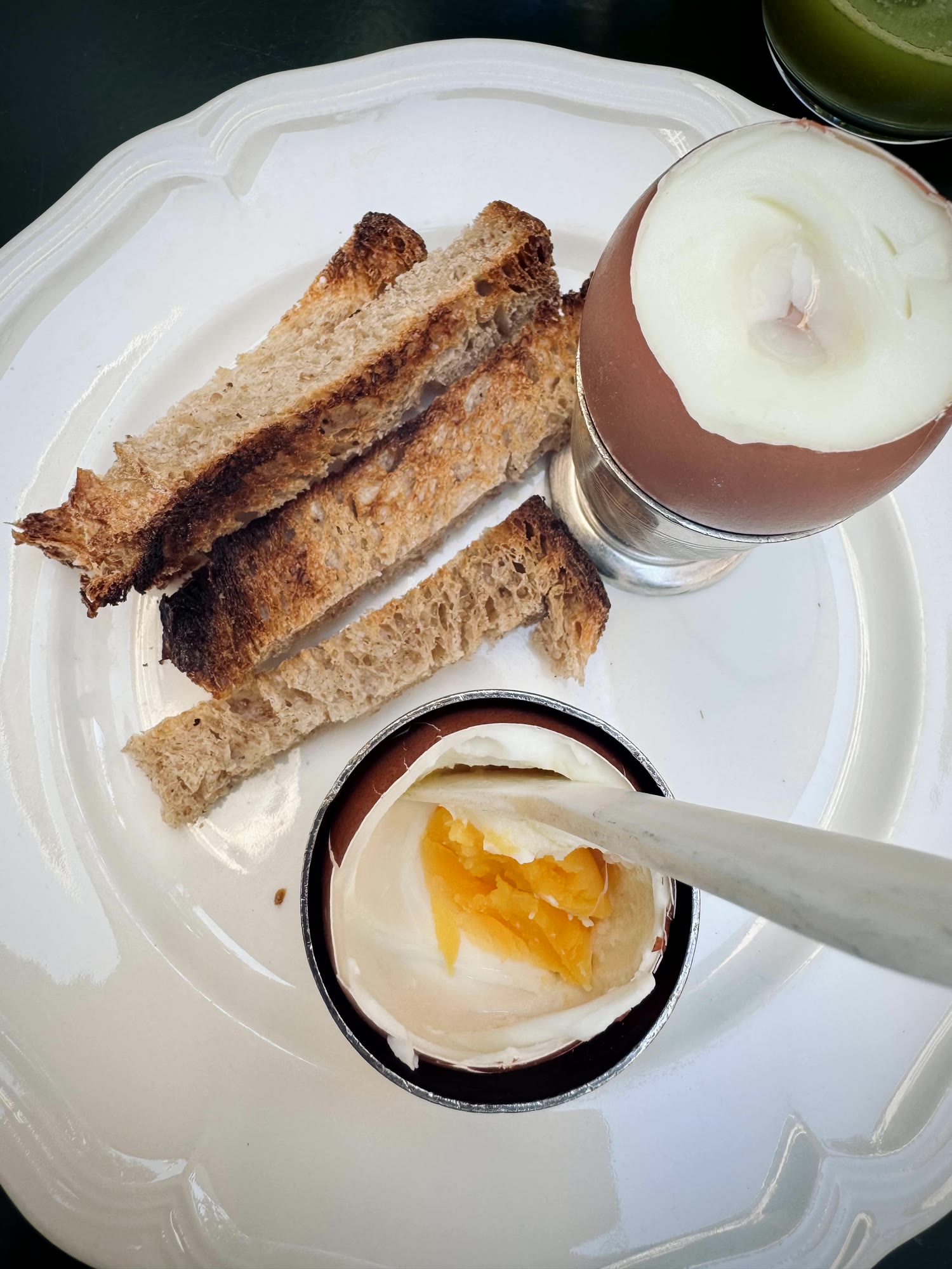 A soft-boiled egg with toast on white china, breakfast made in the house
