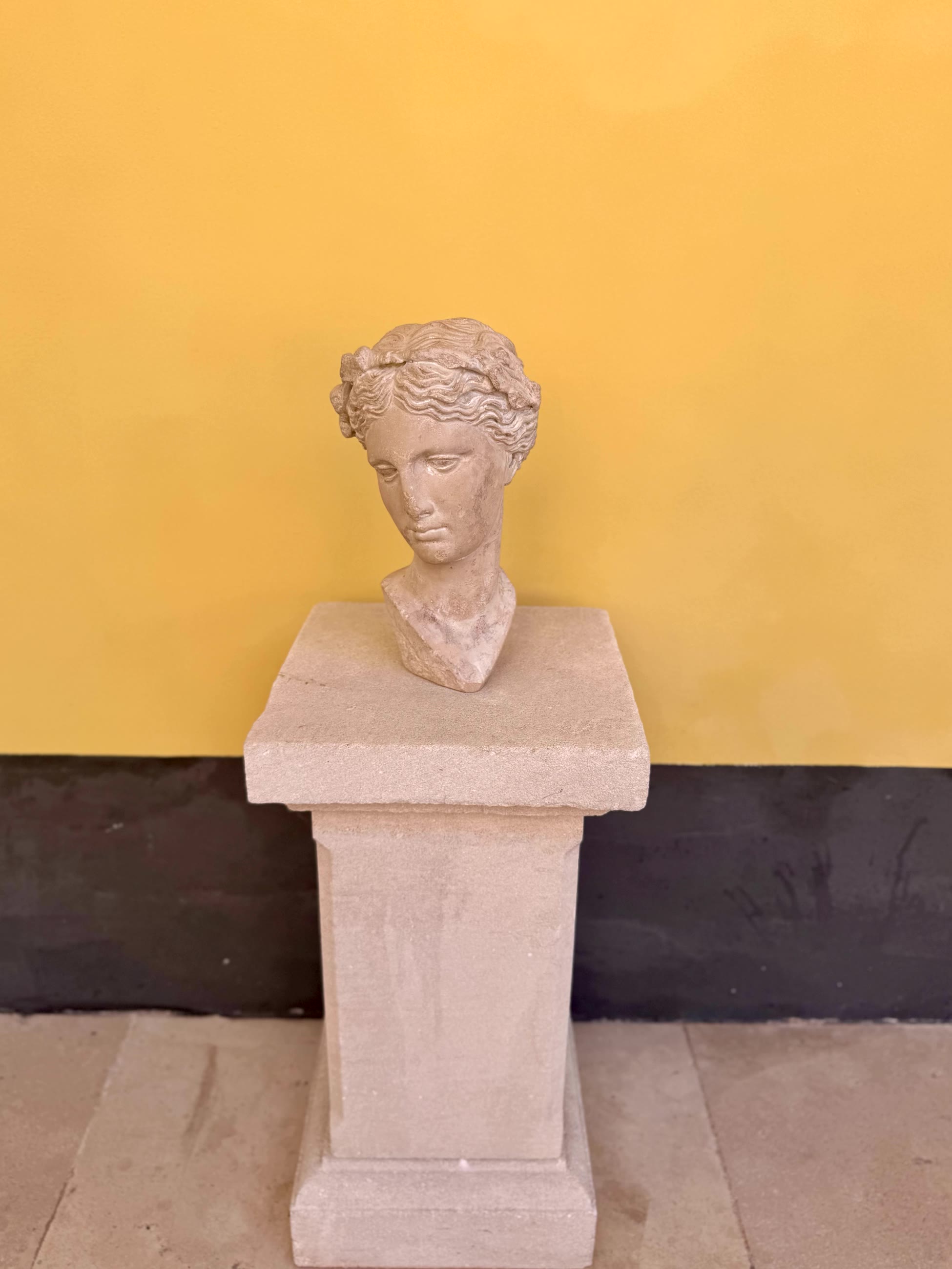 A classical stone head on a pedestal against a yellow wall, Hôtel du Couvent