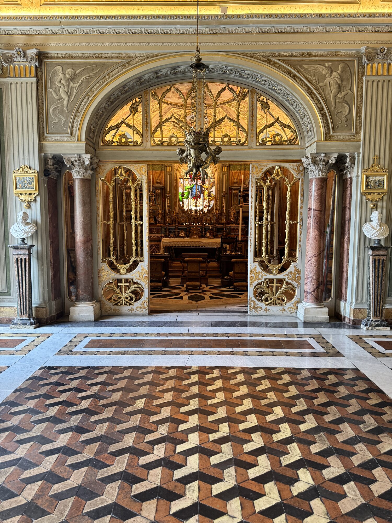 A cosmatesque marble floor and gilded doorway inside a Roman palazzo