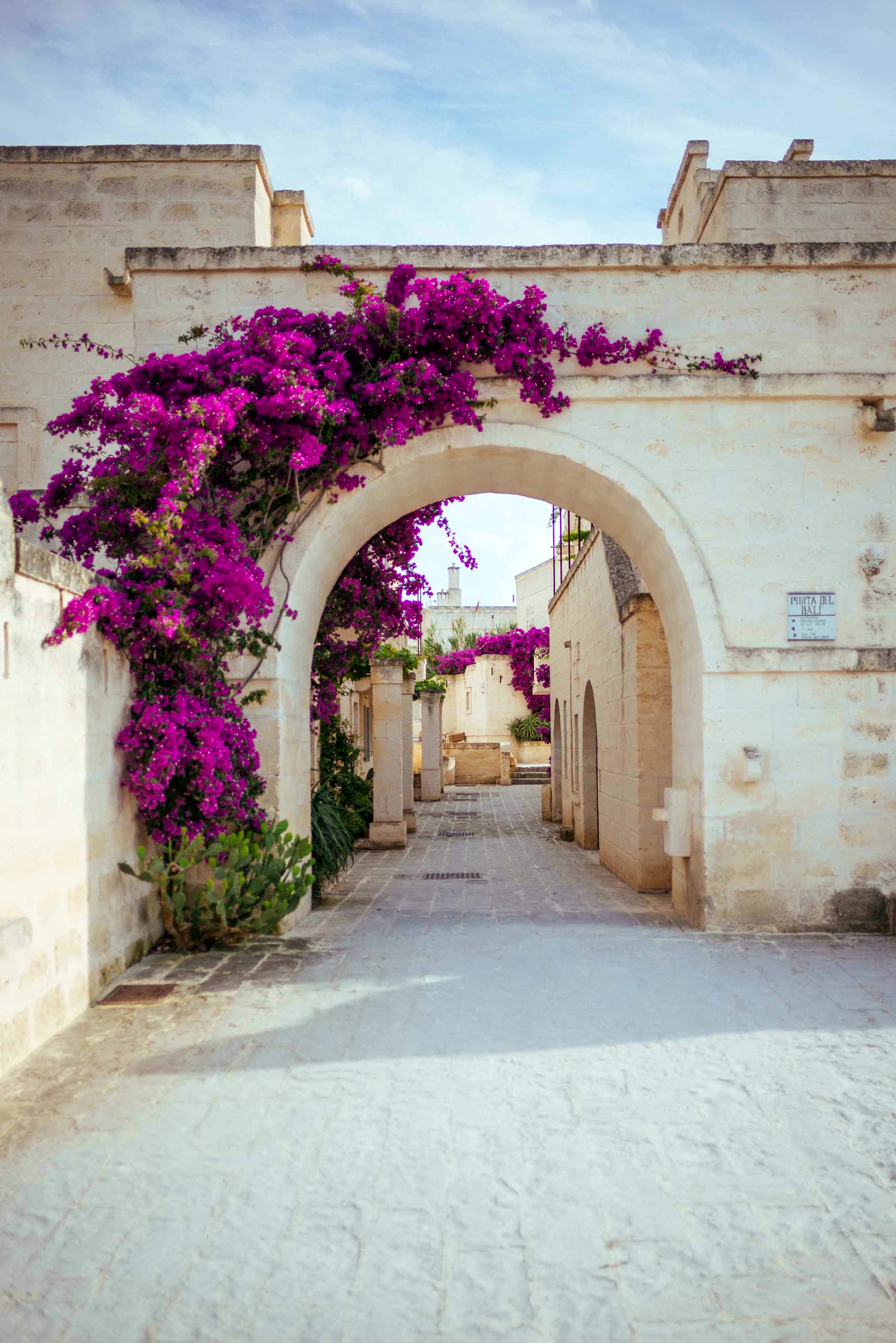 The Porta del Balì at Borgo Egnazia, bougainvillea flowering over a pale stone arch and whitewashed lane