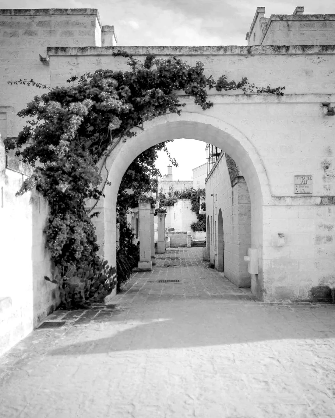 A stone arch with the street continuing beyond it, Puglia